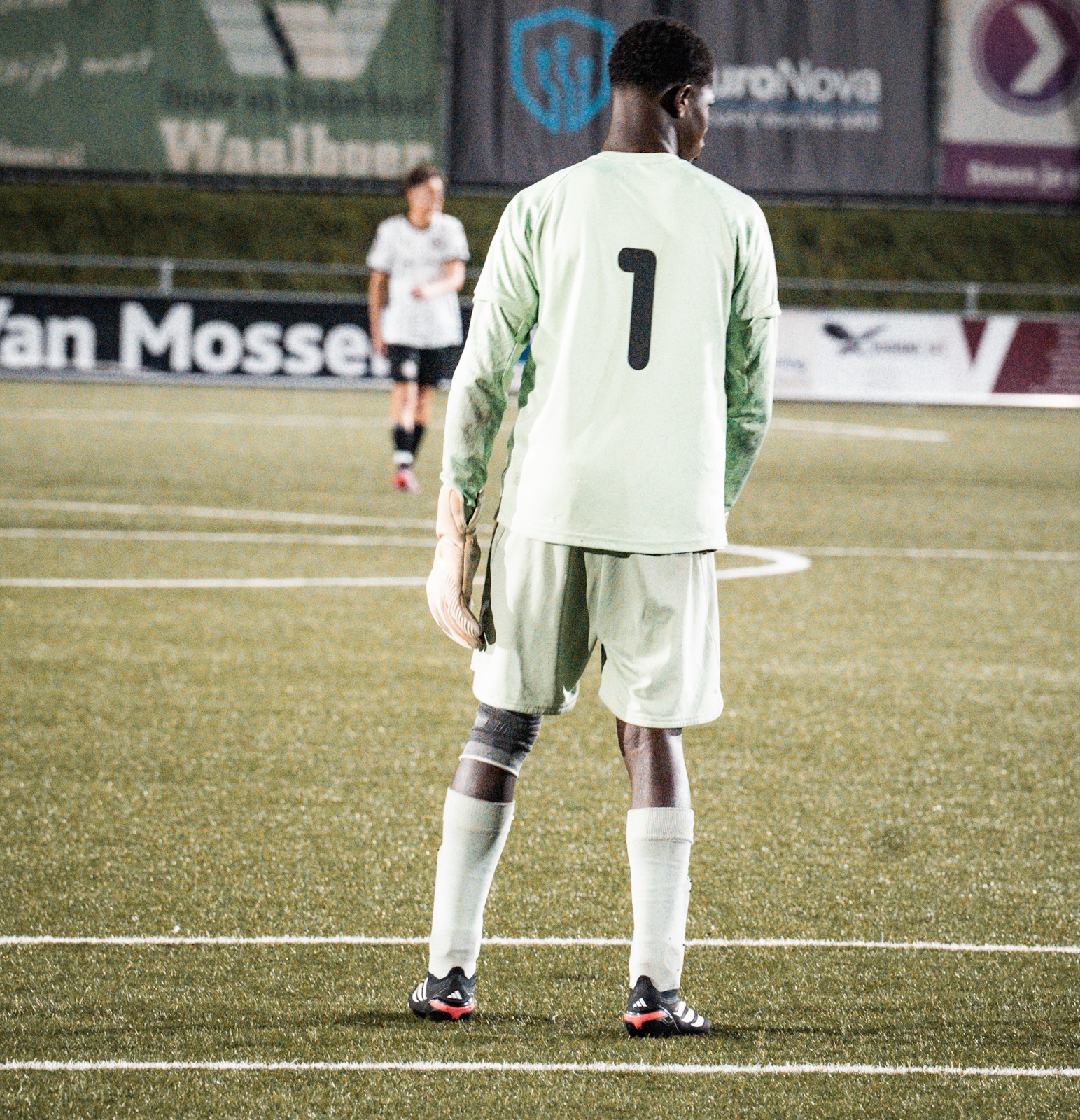 Keeper met rugnummer 1 op het veld onder het stadionlicht