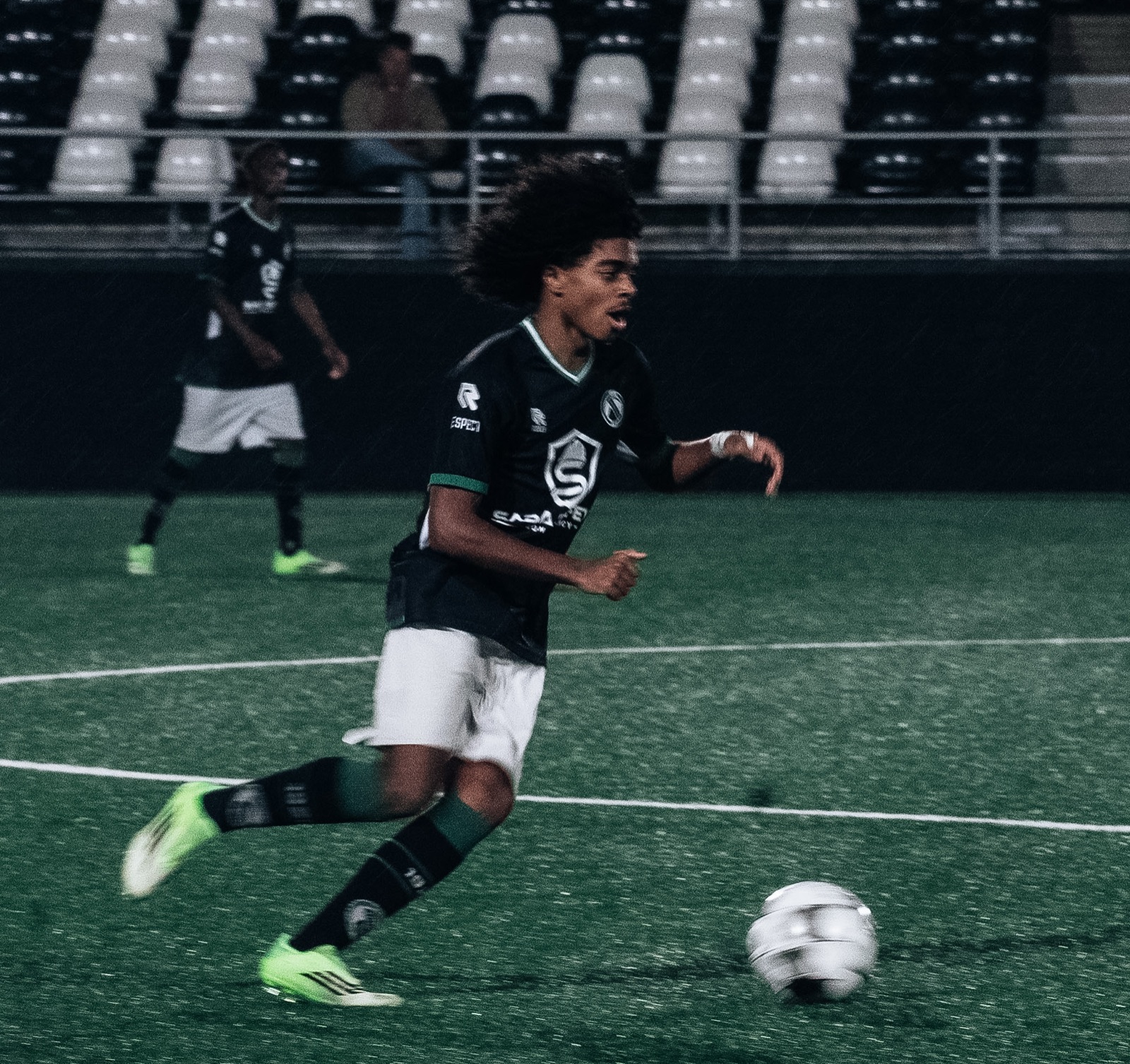 Speler in groen-zwart tenue sprint met de bal